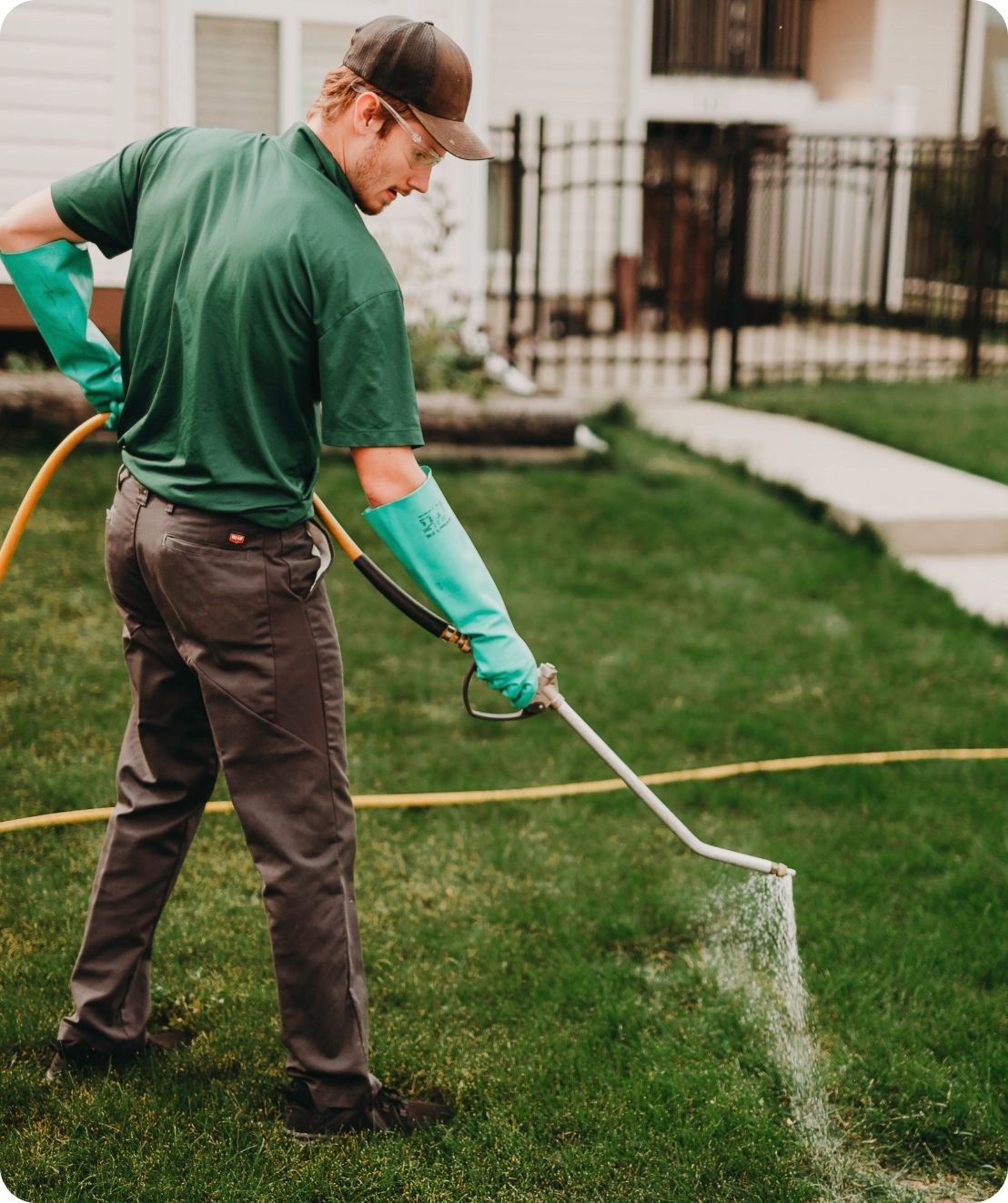 tech (Aidan) sprays weed control on front lawn of home